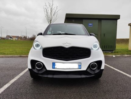 Vue avant droite de la microvoiture blanc toit noir stationnée