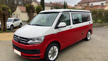 Vue avant droite du van bicolore avec jantes blanches garé sur aire de service
